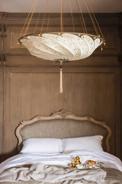 Fortuny Scudo Saraceno Classic elfenbeinweiße Seidenleuchte in einem Hotelzimmer